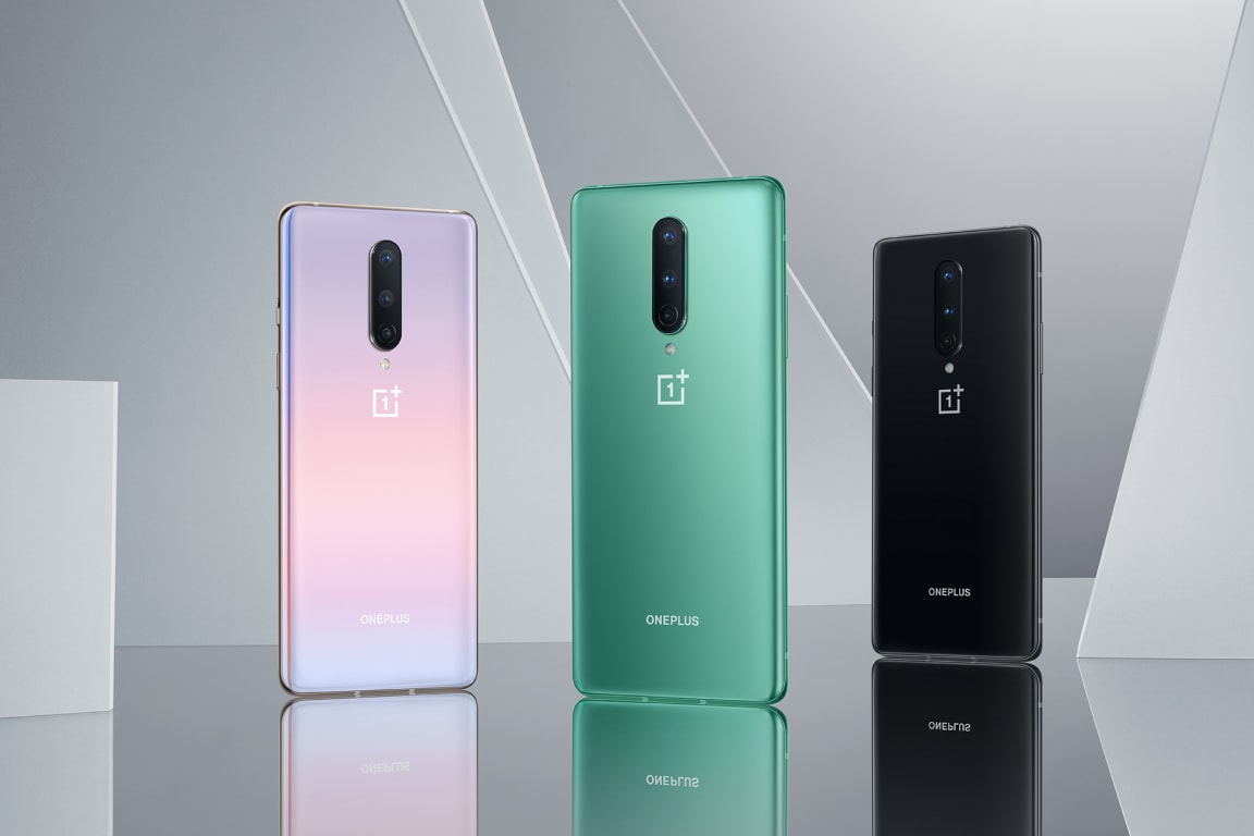 Three colorful OnePlus smartphones in pink, green, and black.